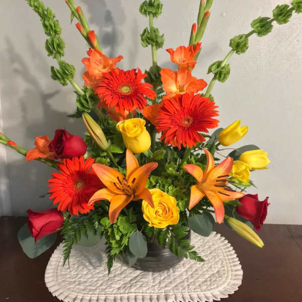 Mixed bouquet with red and yellow roses, orange lilies, and gerbera daisies in a vase