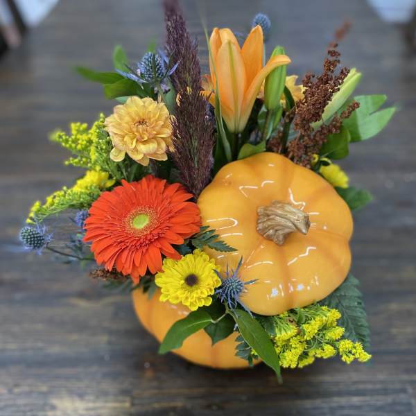 Fall floral arrangement with orange pumpkin decor and mixed blooms