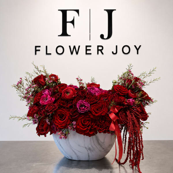 Red and pink rose arrangement in a white marble-look bowl vase