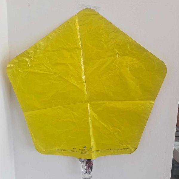 Yellow star-shaped foil balloon against a white wall