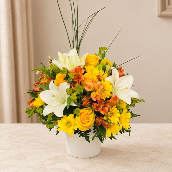 Yellow and white mixed flower arrangement in a white vase