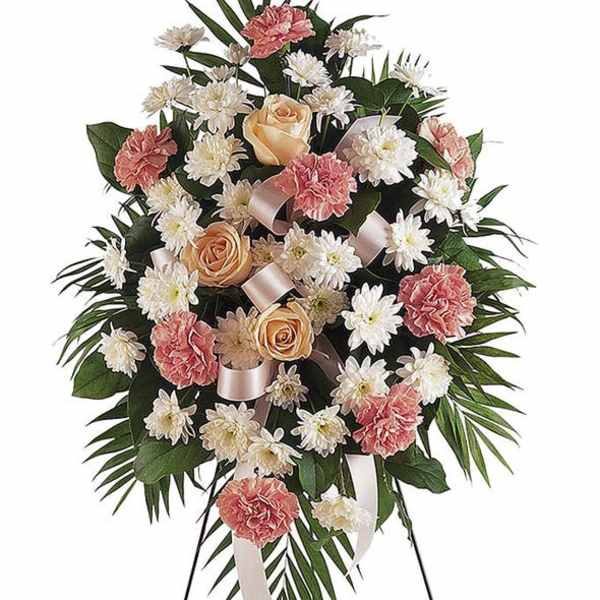 Standing floral spray with pink carnations, peach roses, and white daisies