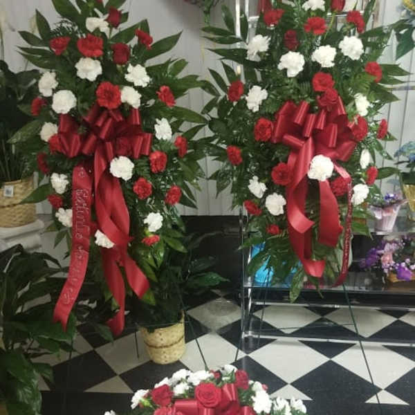 Three red and white floral standing sprays with ribbon bows