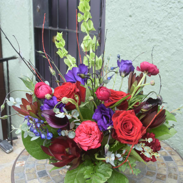 Mixed bouquet with red roses, purple blooms, and dark calla lilies