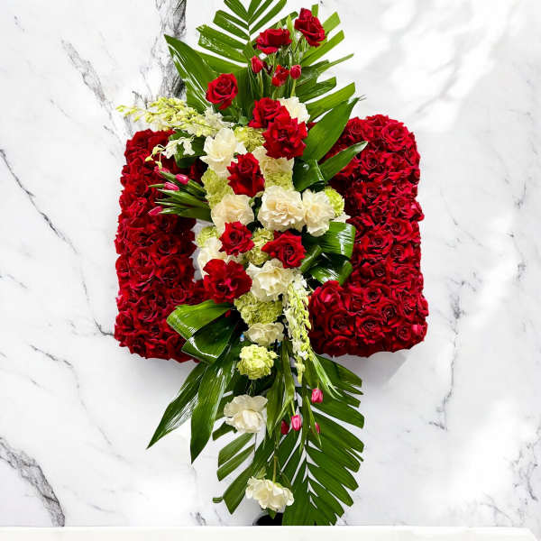 Red and white floral cross with palm leaves on a marble background