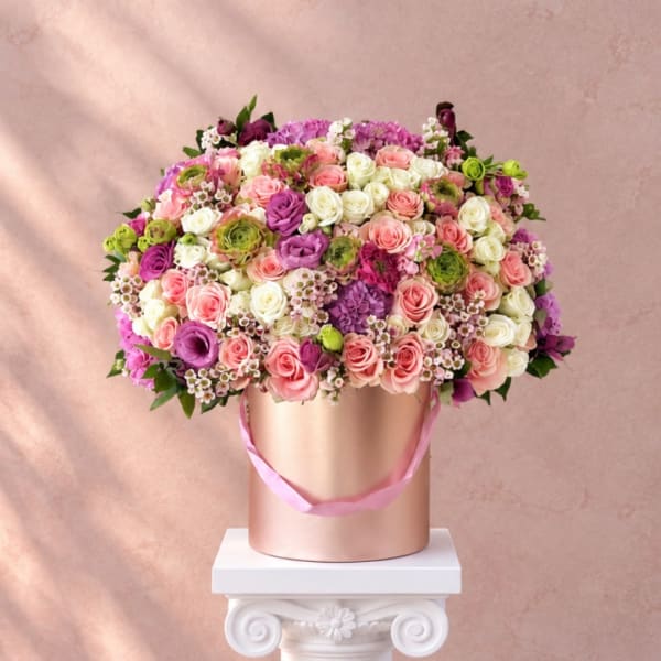 Large bouquet of pink, white, and purple roses in a gold hat box