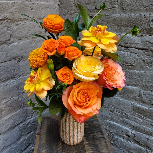 Orange and yellow flower arrangement in a striped ceramic vase