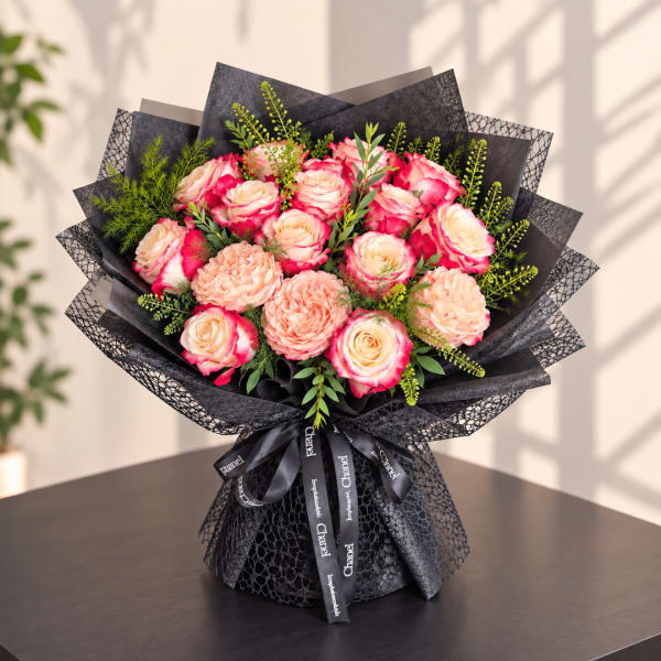 Bouquet of pink and cream roses wrapped in black paper