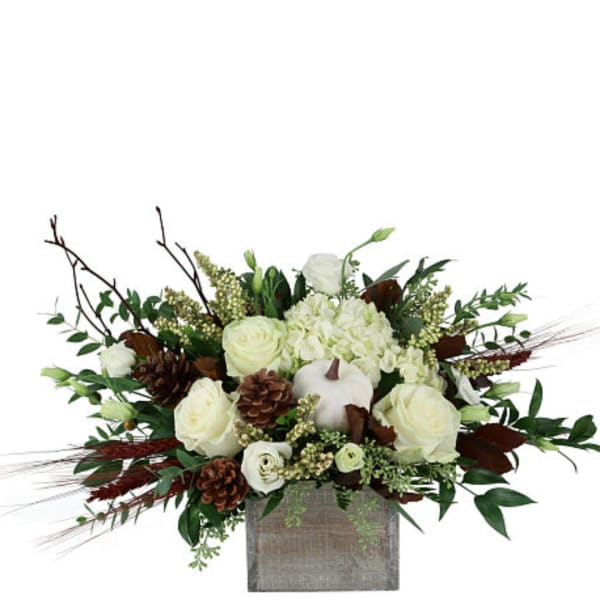 White roses and hydrangeas in a square vase with pinecones
