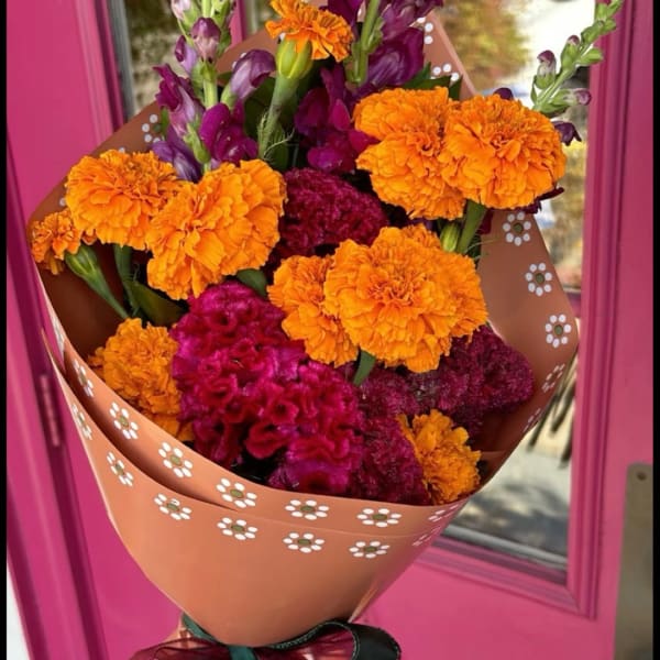 Bouquet of orange marigolds and magenta cockscomb in patterned wrap