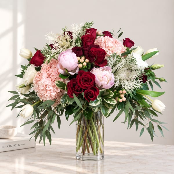 Mixed bouquet of red, pink, and white flowers in a clear glass vase