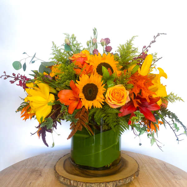 Bright mixed bouquet with sunflowers, lilies, and roses in a green vase