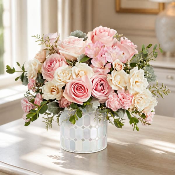 Pink and cream rose arrangement in a patterned white vase