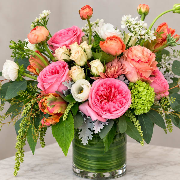 Mixed pink, peach, and white flowers arranged in a glass vase