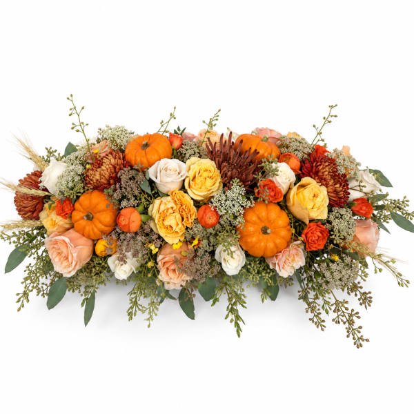 Low floral centerpiece with orange pumpkins and roses in autumn colors
