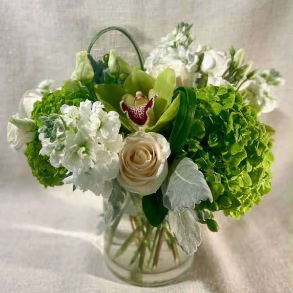 Green and white floral arrangement in a clear glass vase