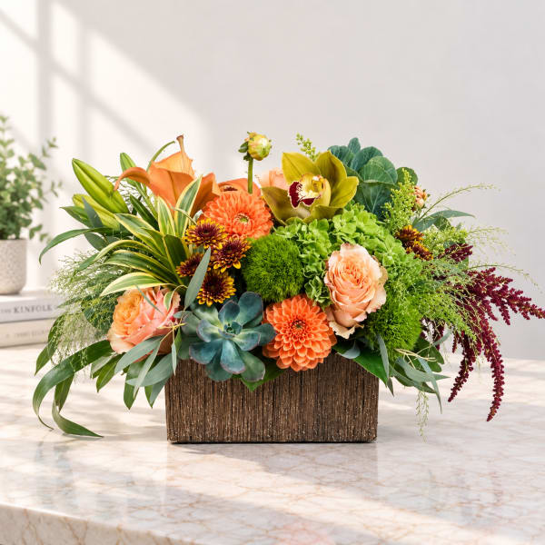 Mixed floral arrangement in a rectangular wooden container with orange and green blooms