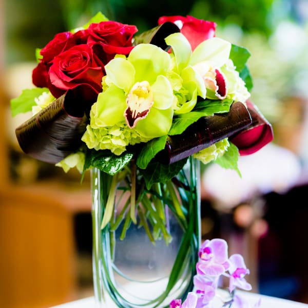 Bouquet of red roses and green orchids in a glass vase