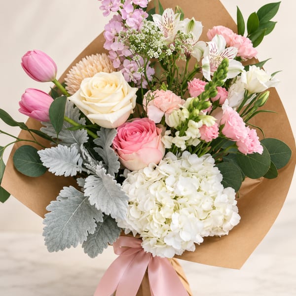 Pink and white mixed bouquet wrapped in brown paper with a pink ribbon