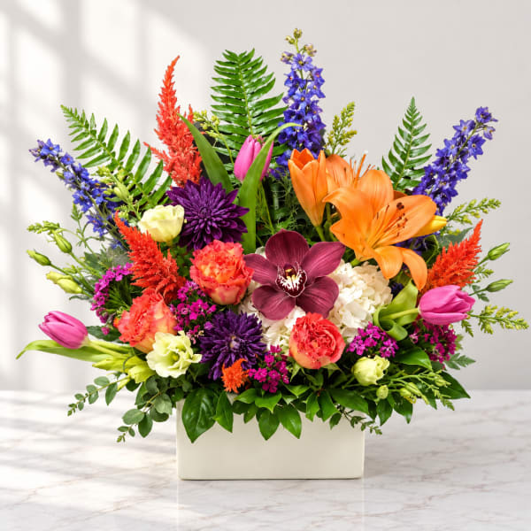 Colorful mixed flower arrangement in a white rectangular vase