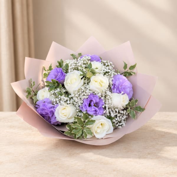 Bouquet of white roses and purple blooms wrapped in pink paper