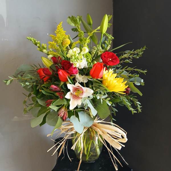Mixed bouquet of red, yellow, and white flowers in a glass vase