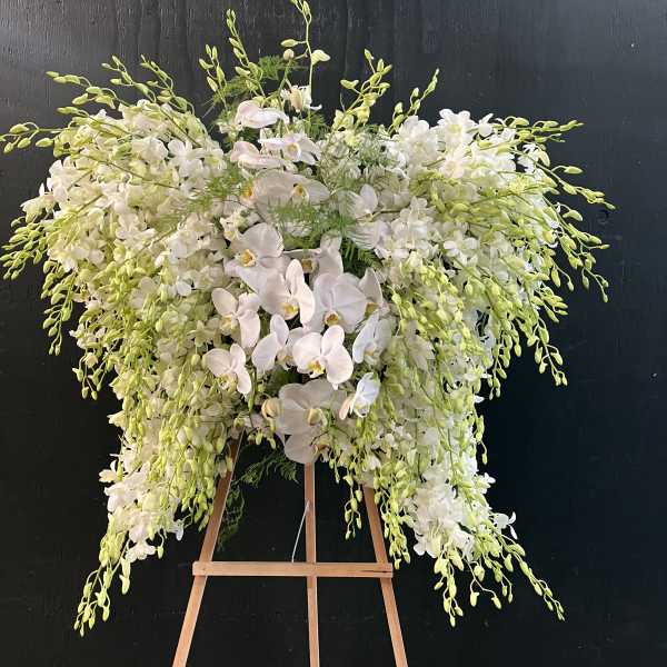 Large white orchid arrangement on a wooden easel