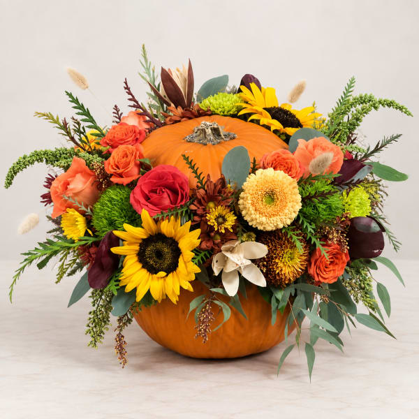 Pumpkin centerpiece with sunflowers, roses, and mums