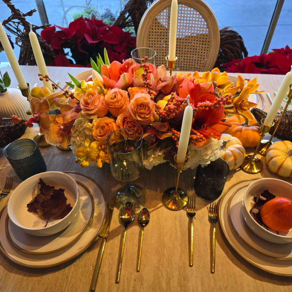 Autumn centerpiece with orange flowers and candles on a dining table
