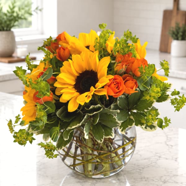 Sunflowers and orange roses in a clear glass vase