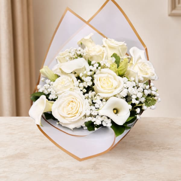 White roses and calla lilies arranged in a wrapped bouquet