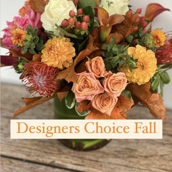 Fall bouquet with peach roses, yellow blooms, and orange foliage in a vase