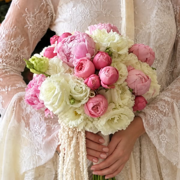 Bride holding a pink and white bouquet of peonies and roses