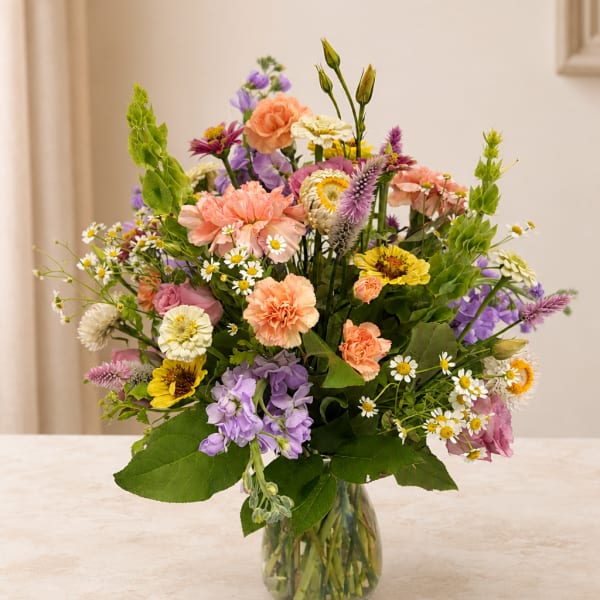 Mixed bouquet of pastel flowers in a clear glass vase