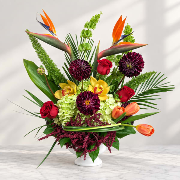 Tropical bouquet with red roses, orchids, tulips, and a white vase