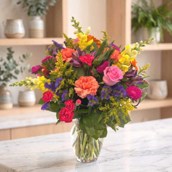 Colorful mixed bouquet in a clear glass vase on a countertop