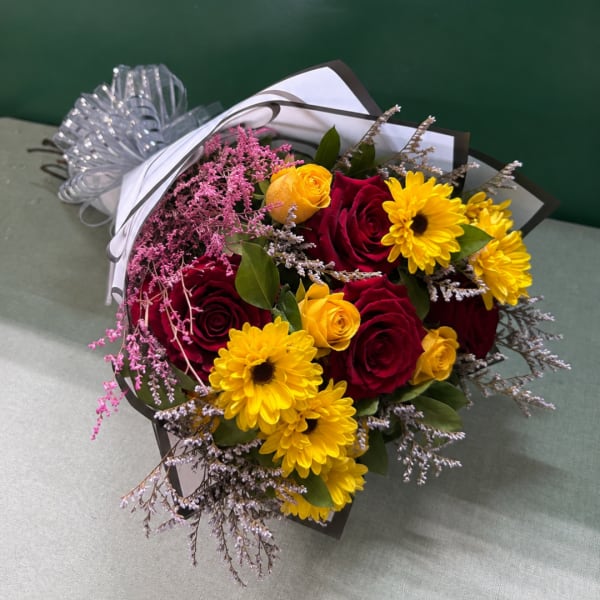 Bouquet of red and yellow roses with yellow daisies wrapped in paper