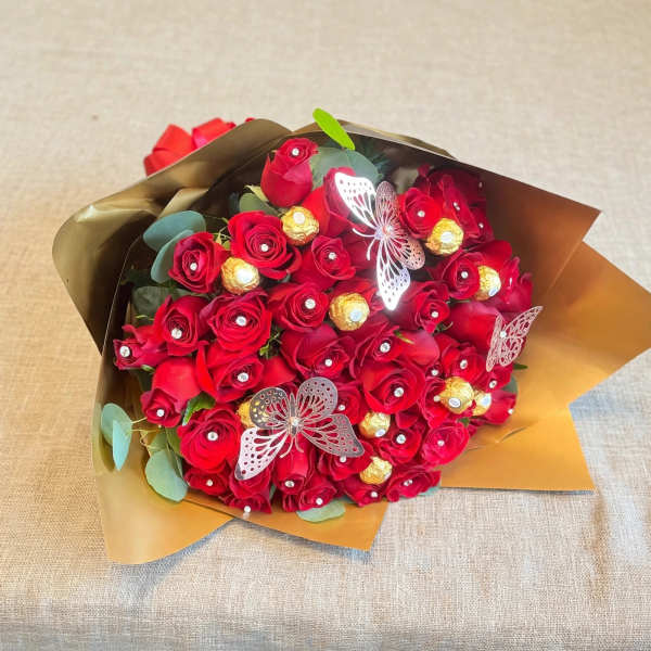 Bouquet of red roses with gold-wrapped chocolates and butterfly accents