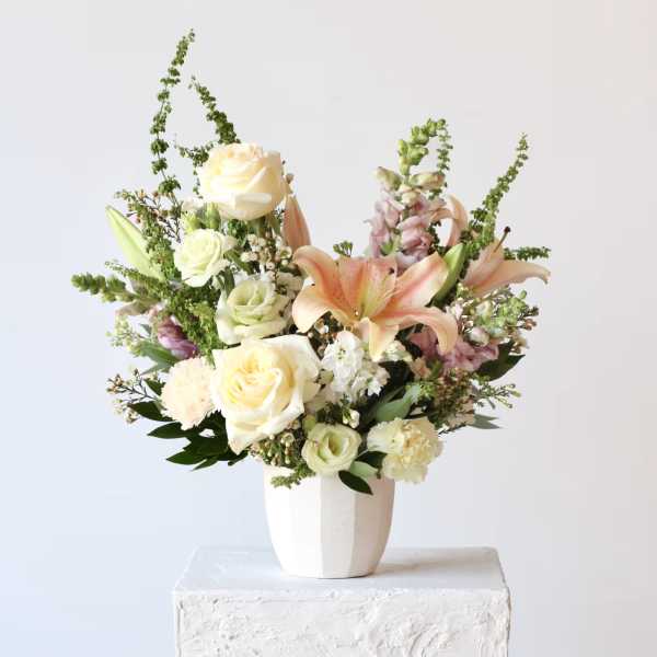 Mixed bouquet of roses and lilies in a white vase
