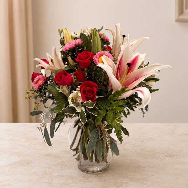 Red roses and pink lilies in a clear glass vase