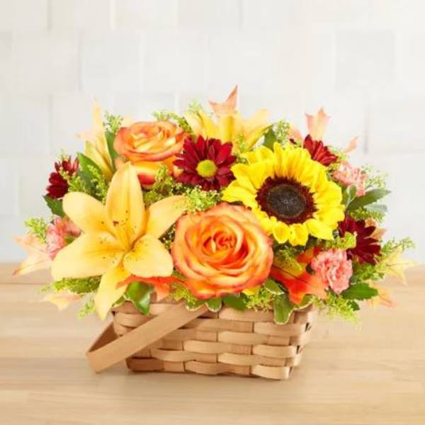 Basket arrangement with sunflowers, roses, lilies, and red daisies