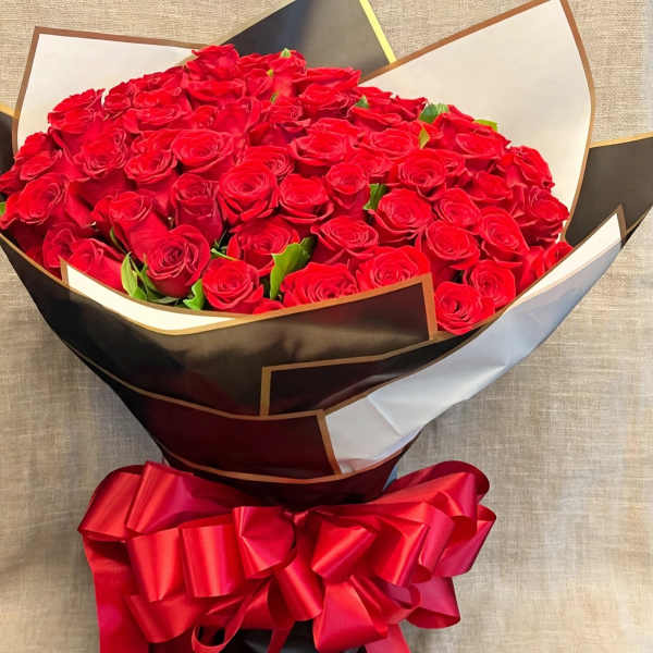 Large bouquet of red roses wrapped in black and white paper with a red ribbon