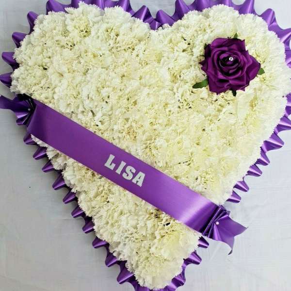 Heart-shaped white carnation arrangement with a purple rose and ribbon