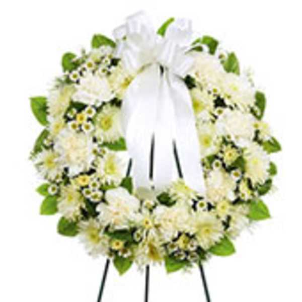 White floral wreath on a standing easel with a white ribbon