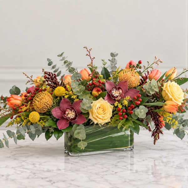 Mixed bouquet in a rectangular glass vase with yellow roses and burgundy orchids