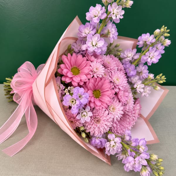 Pink and lavender bouquet wrapped in pale pink paper with a ribbon