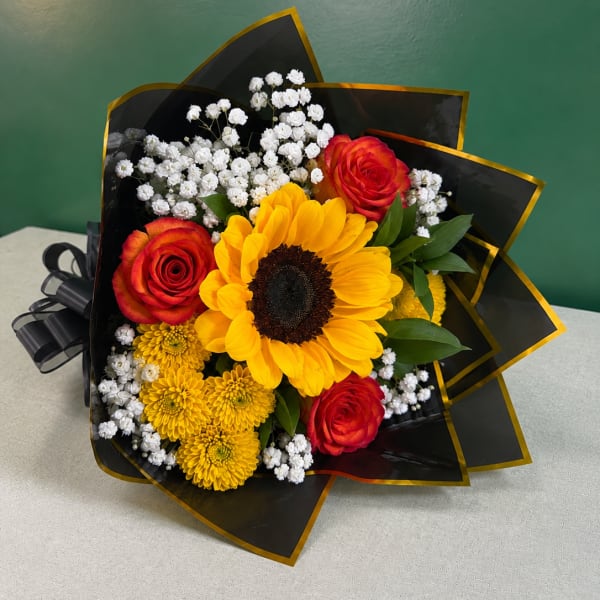Bouquet of sunflowers, red roses, and white baby's breath in black wrap