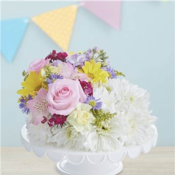 Pastel mixed flower arrangement in a white pedestal bowl
