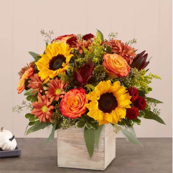 Mixed bouquet with sunflowers, roses, and mums in a wooden cube vase