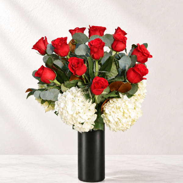 Red roses and white hydrangeas arranged in a black vase
